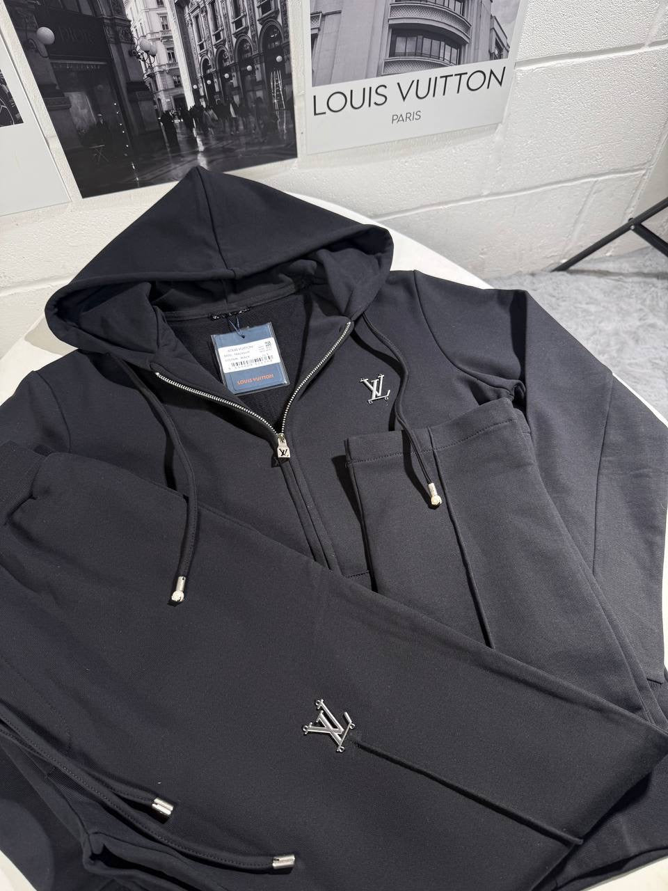 Black tracksuit jacket with drawstring hood, front zip, and small LV logo accents