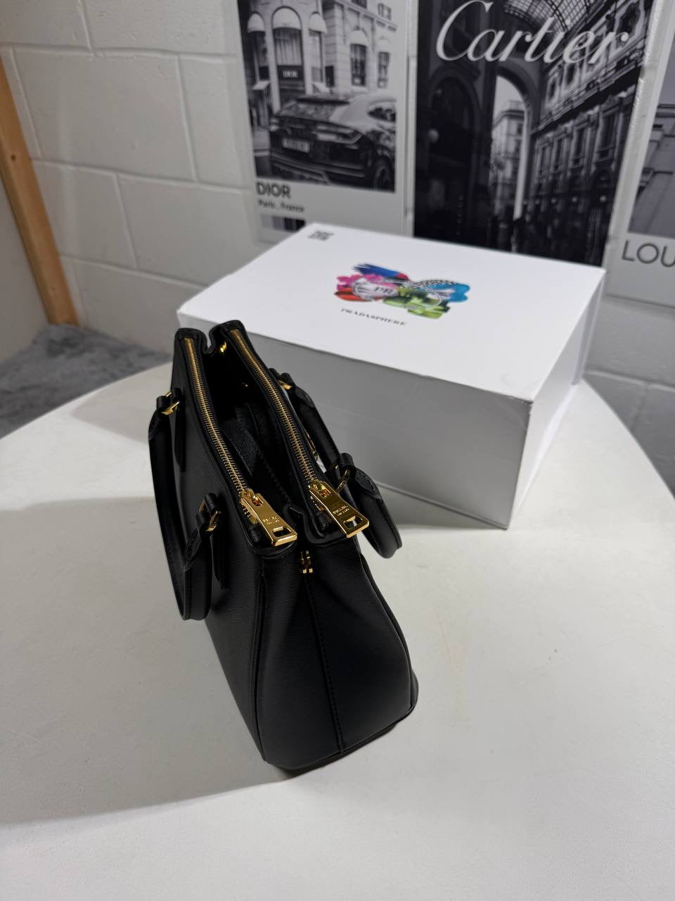 Black LV Alma BB-style bag shown from side, with gold-tone clasp and handles