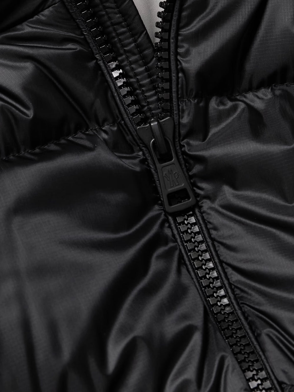 Black jacket close-up: black zipper pull and zipper track detail
