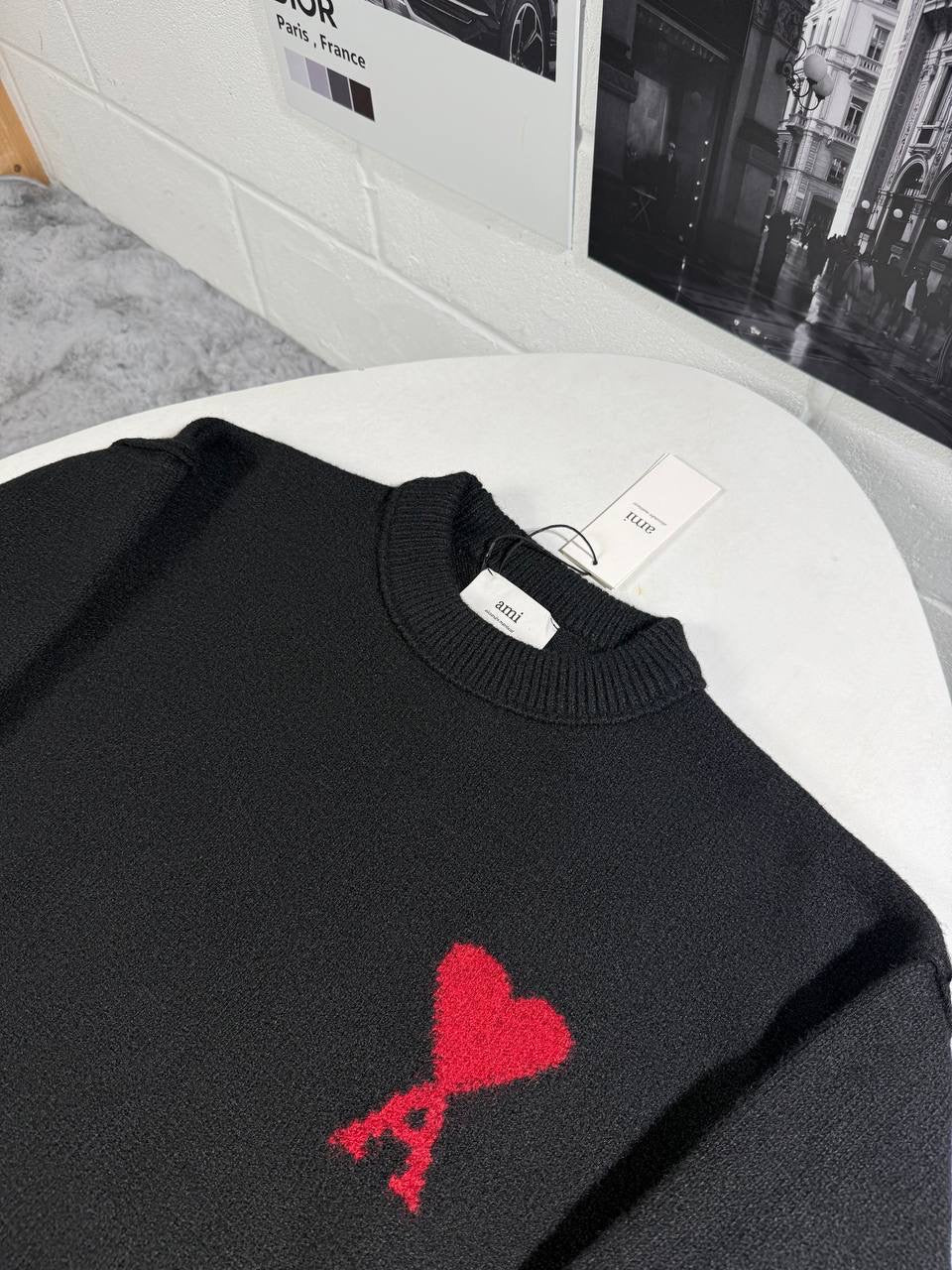 Black knit crewneck jumper with ribbed hem and cuffs, featuring a red heart emblem