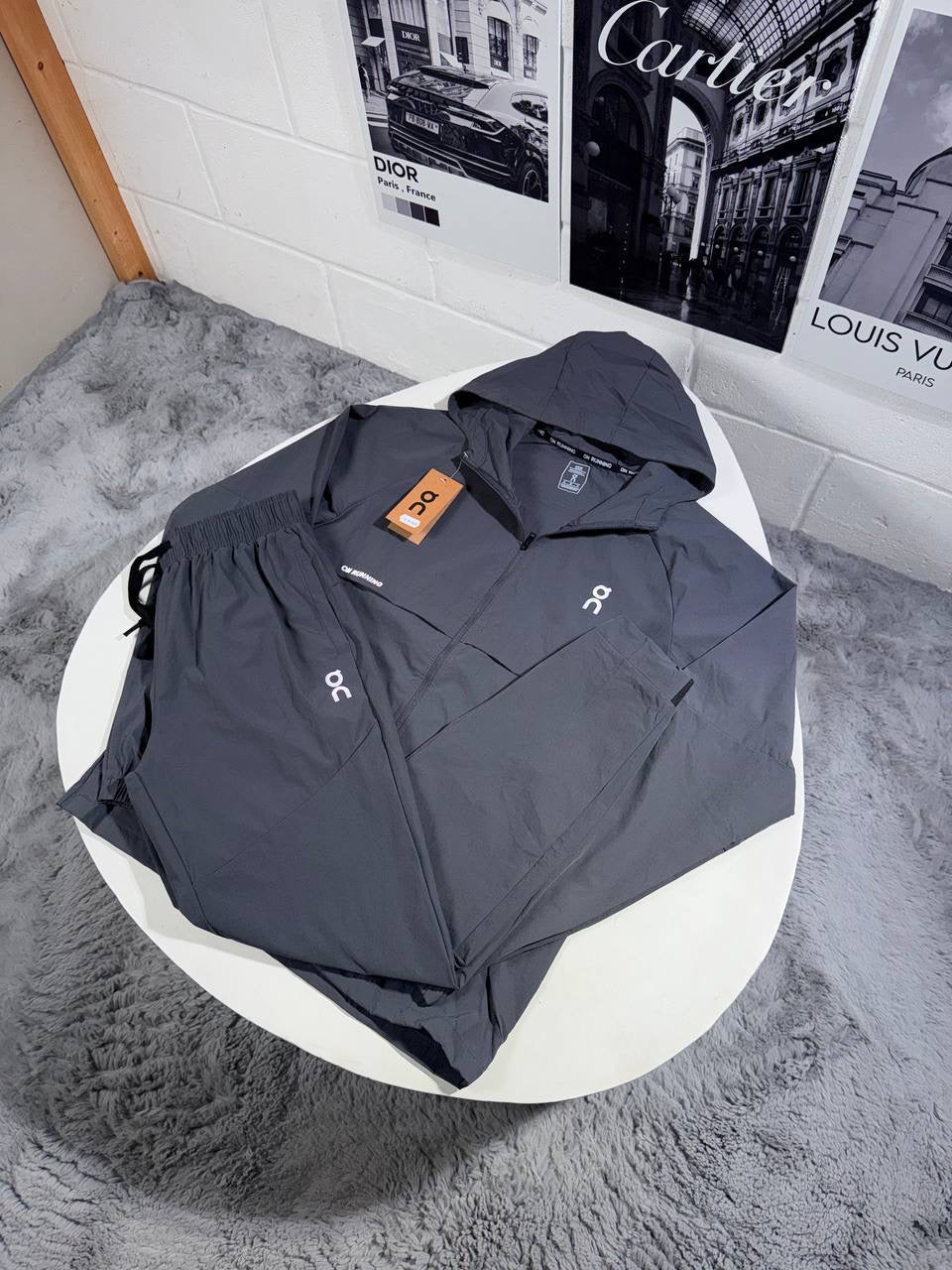 Hooded zip tracksuit jacket in charcoal gray with logo patch and orange tag