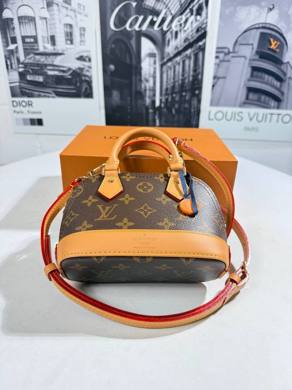 Monogram canvas handbag with tan top handles and red crossbody strap, front view