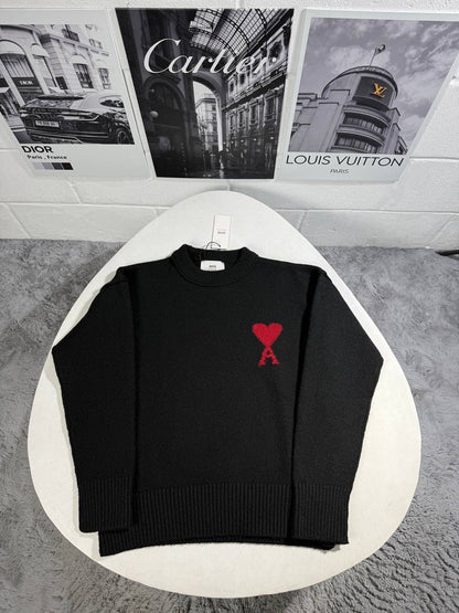 Black knit crewneck sweater with ribbed hem and cuffs, featuring a red heart emblem