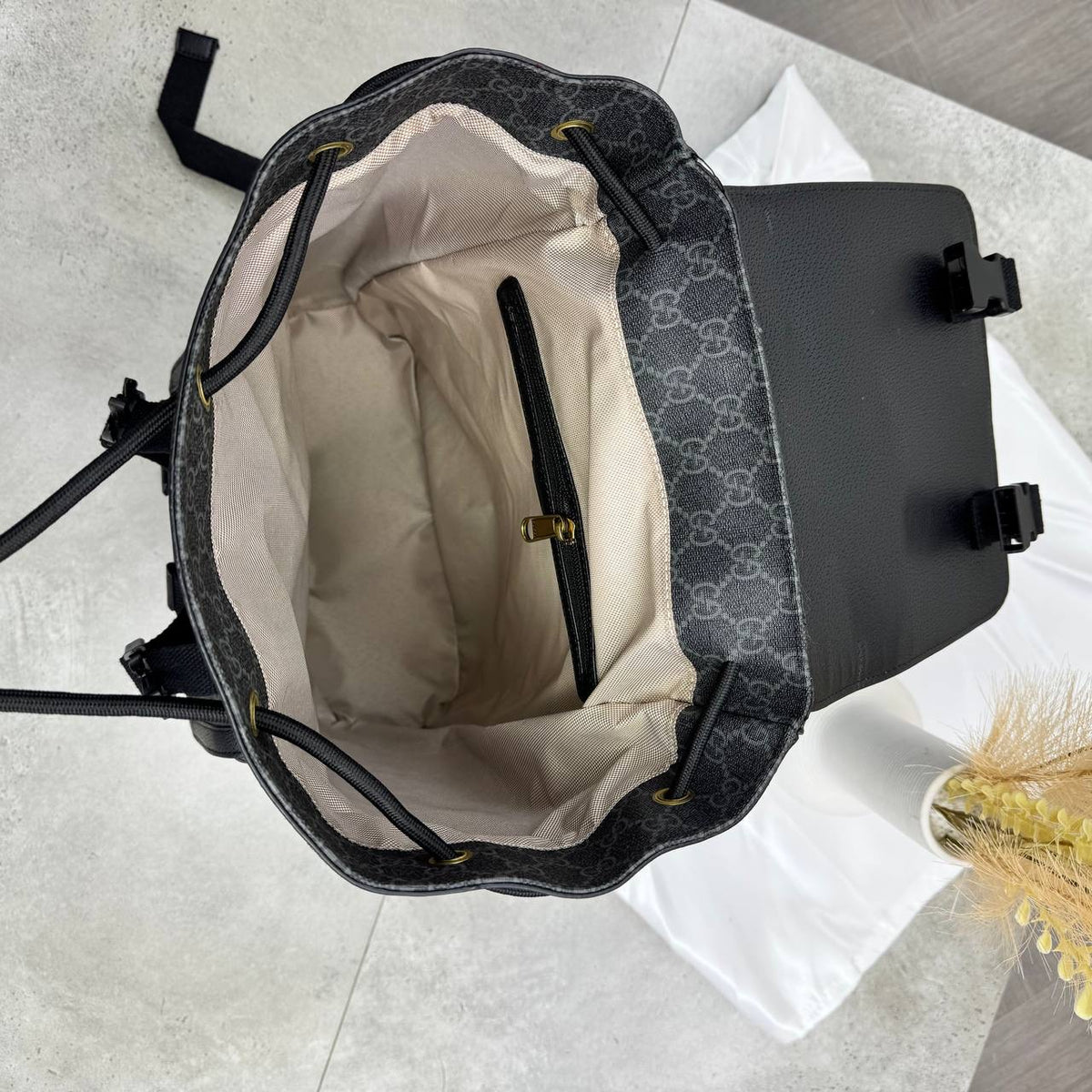 Dark gray GG backpack open top with cream fabric lining and zipper pocket