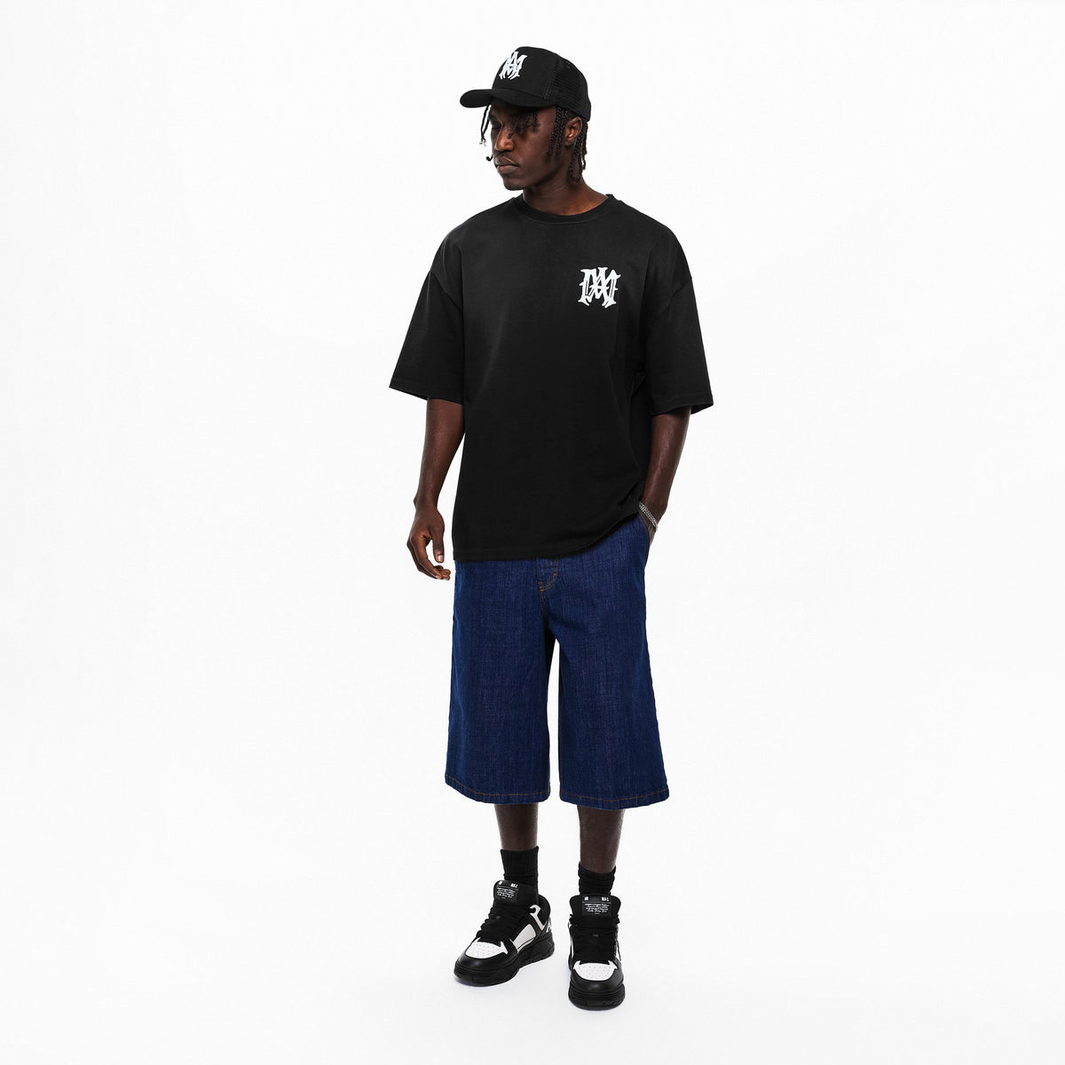Model wearing black/white patch MA chunky trainers with cap, T-shirt, and denim shorts