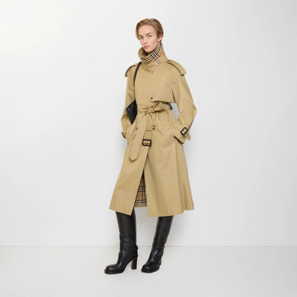 Sand beige trench coat with high collar, belted waist, and buttoned storm flap