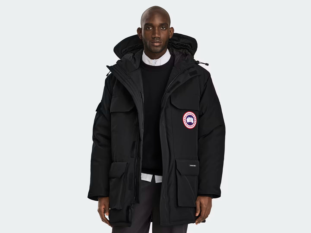 Expedition Parka Black, front view showing logo patch, zip center, and parka silhouette