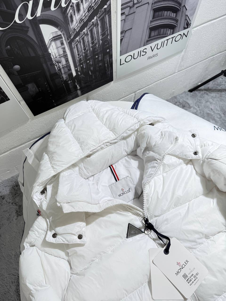 White Moncler puffer jacket with hood, snap pockets, and multicolor stripe detail