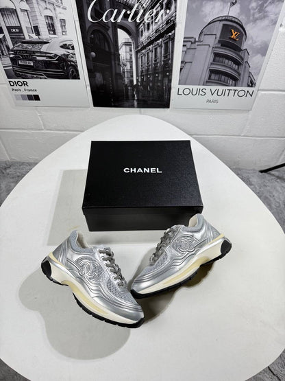 Silver trainers pair with mesh uppers, black trim, and cream-tinted sole accents