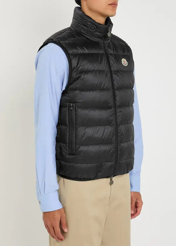 Black quilted gilet with zip front, raised collar, and logo badge on chest