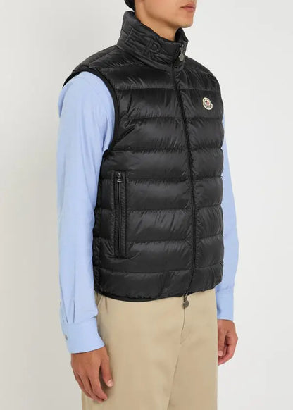 Black quilted gilet with zip front, raised collar, and logo badge on chest