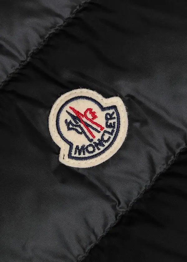 Close-up of Moncler logo patch on black quilted shell gilet fabric