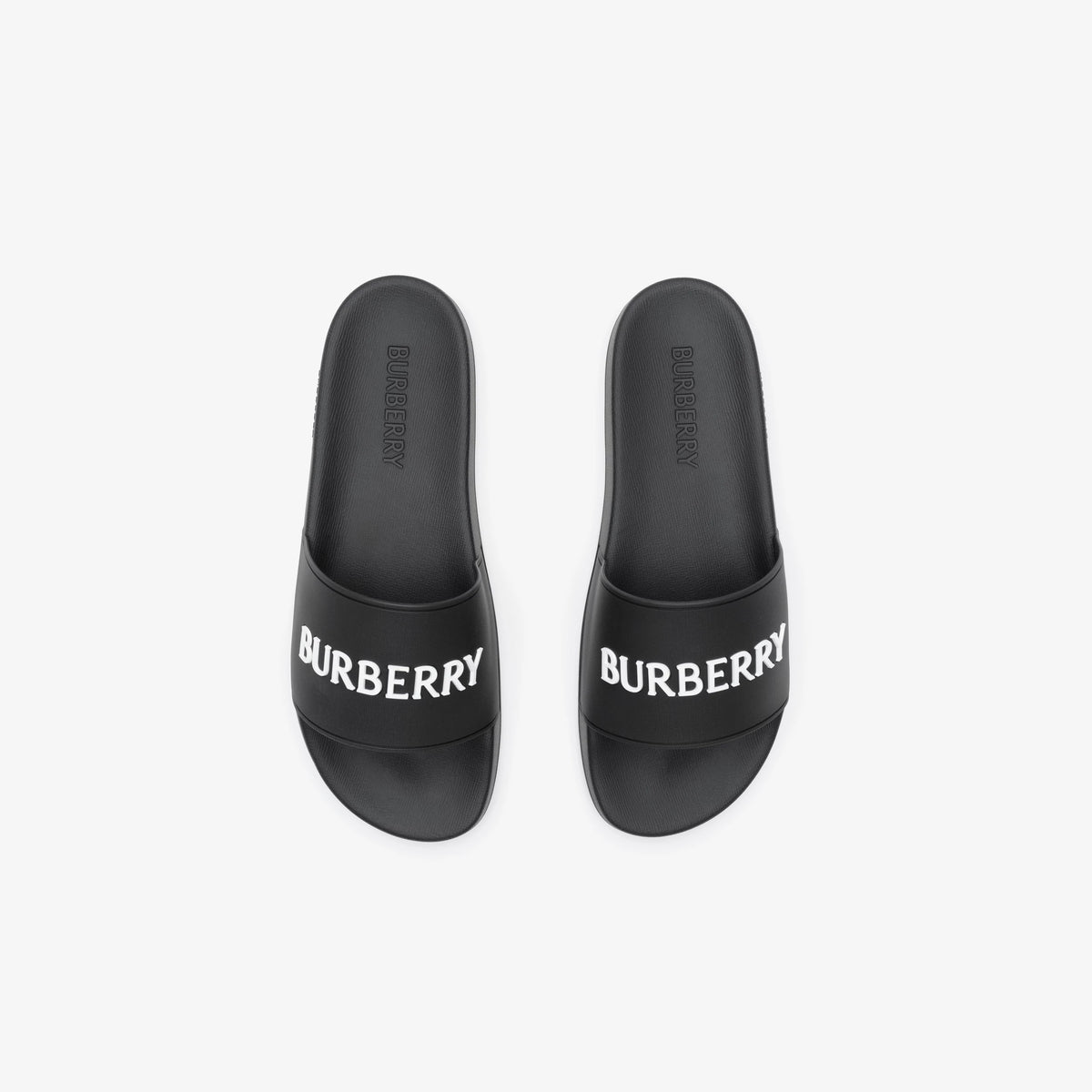 Schwarze Slides mit eingeprägtem BURBERRY-Schriftzug an der Fußfläche
