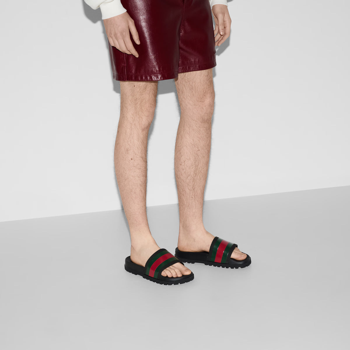 Rubber Web Slide Sandal on foot, black sole with green/red striped strap