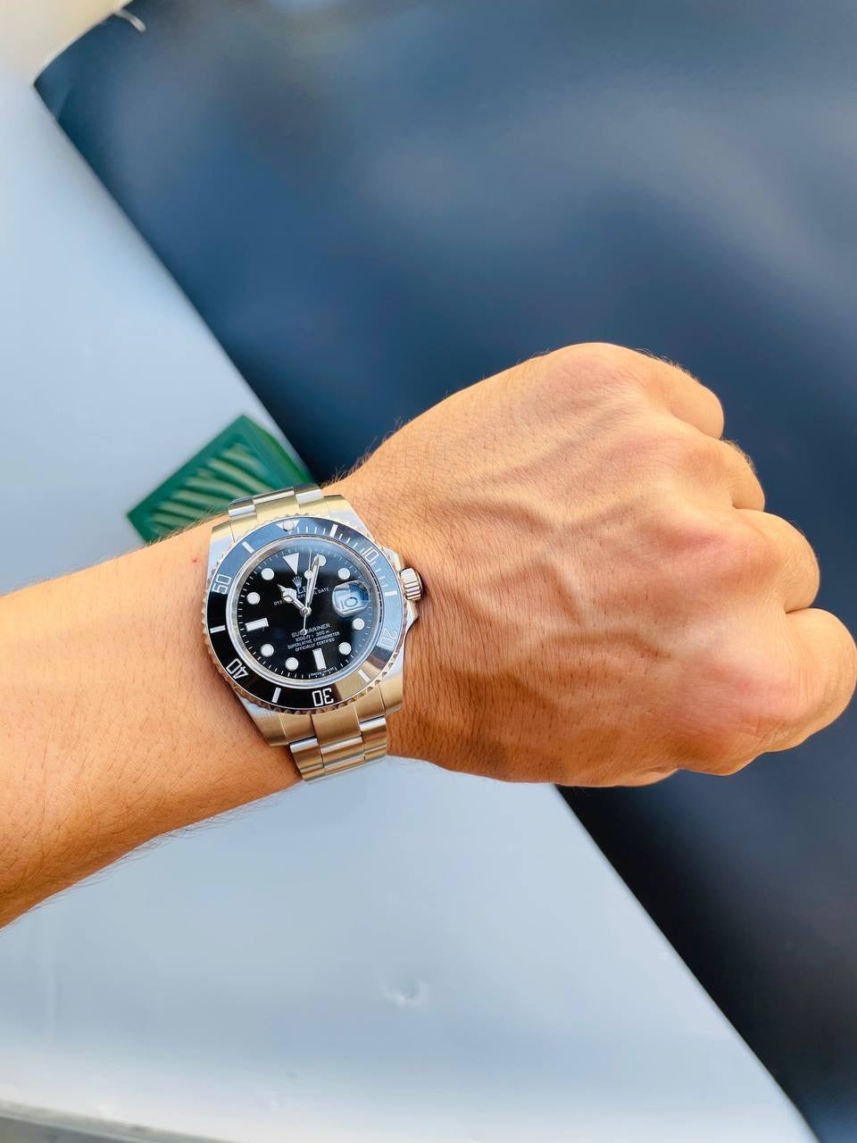 Rolex steel bracelet watch with black dial, bezel markings, and luminous hands