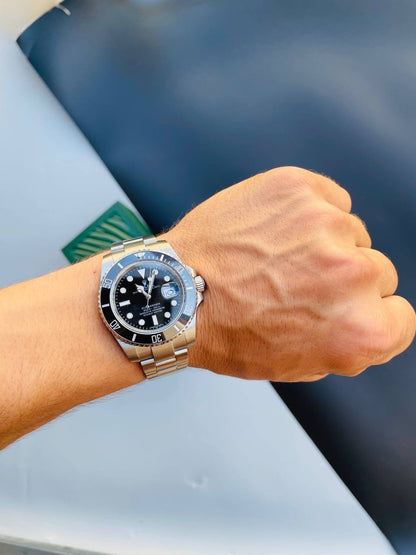 Rolex steel bracelet watch with black dial, bezel markings, and luminous hands