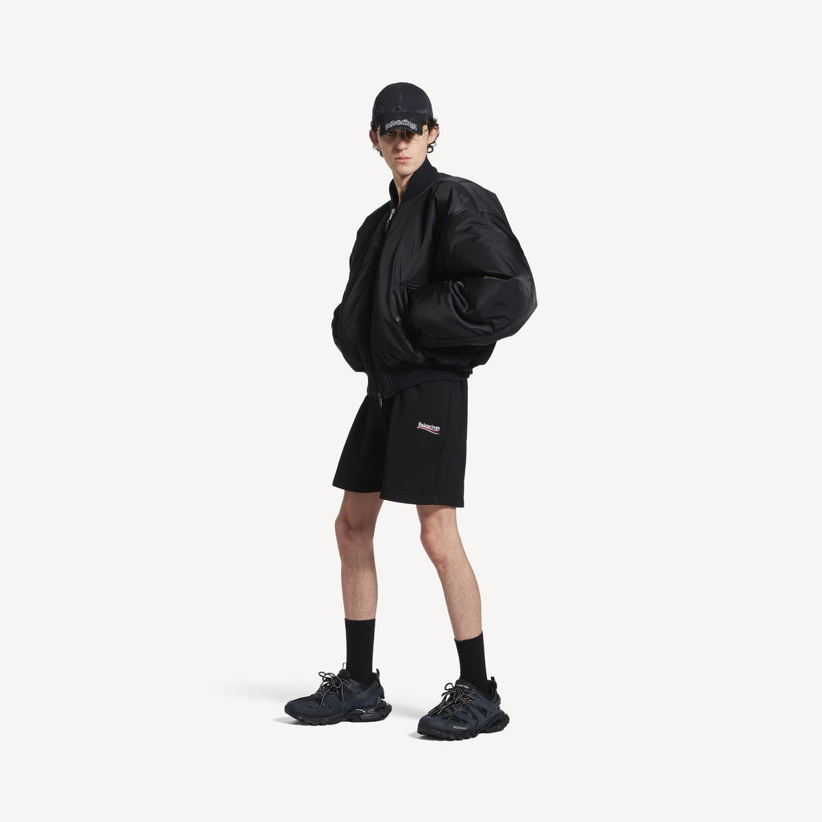 Men's black track sneakers worn with black shorts and crew socks