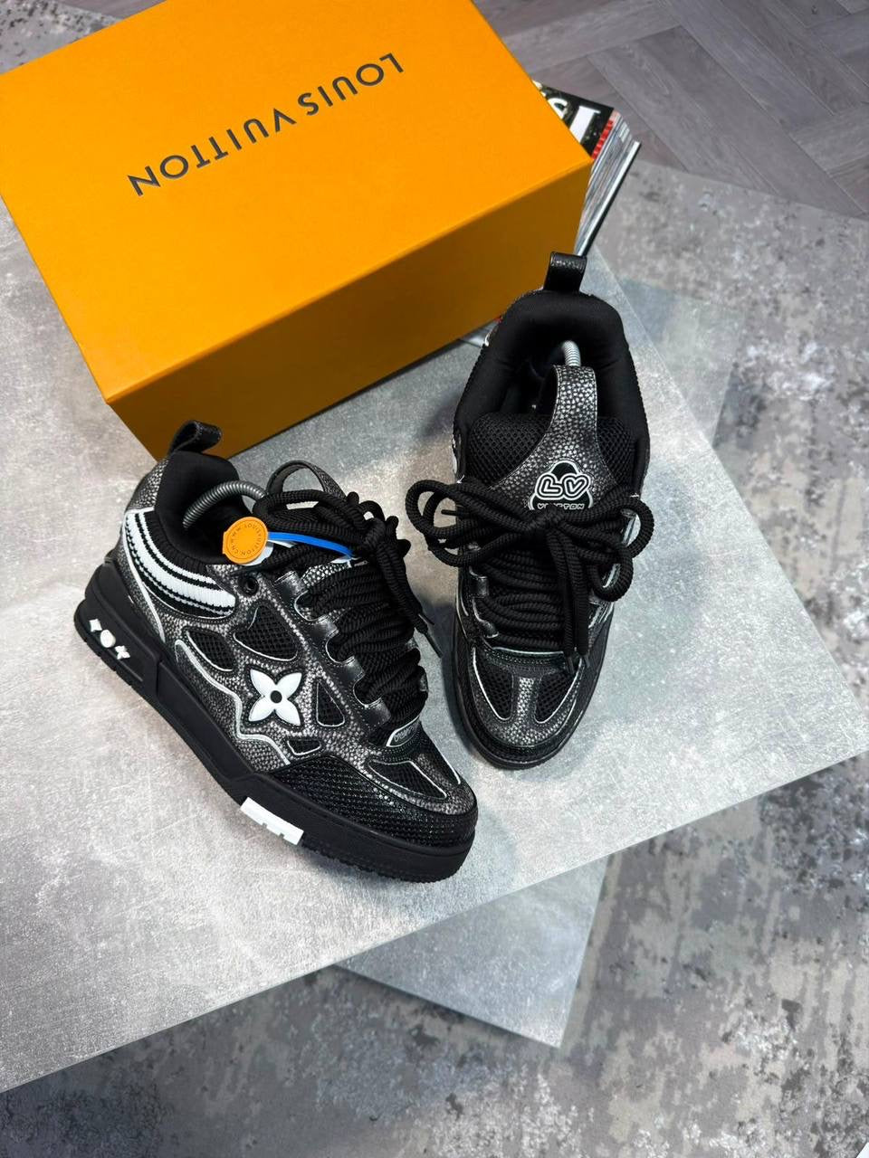 Black skate sneakers with black laces, silver logo flower emblems, chunky sole