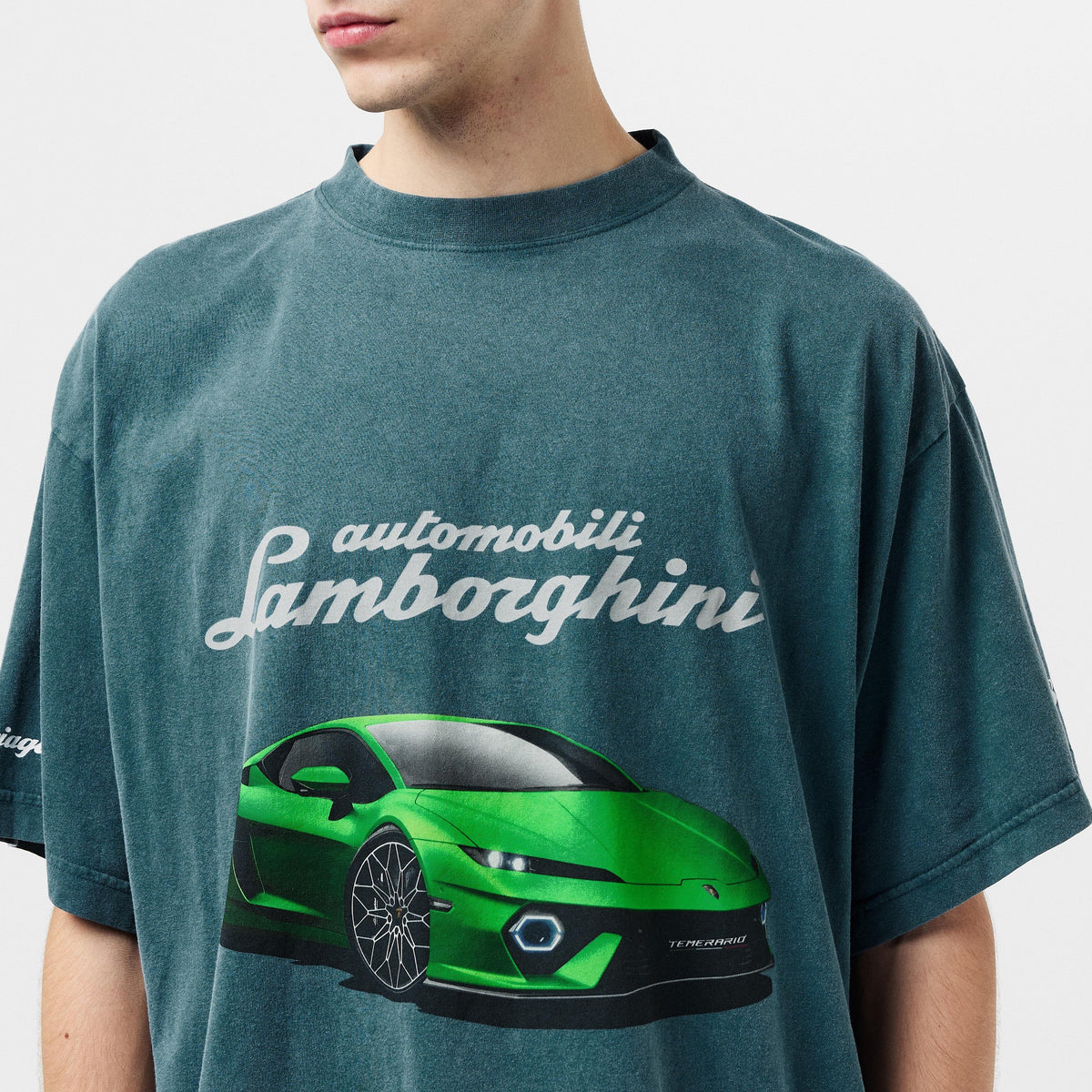 Close-up: petrol blue T-shirt with white cursive Automobili Lamborghini logo and green car