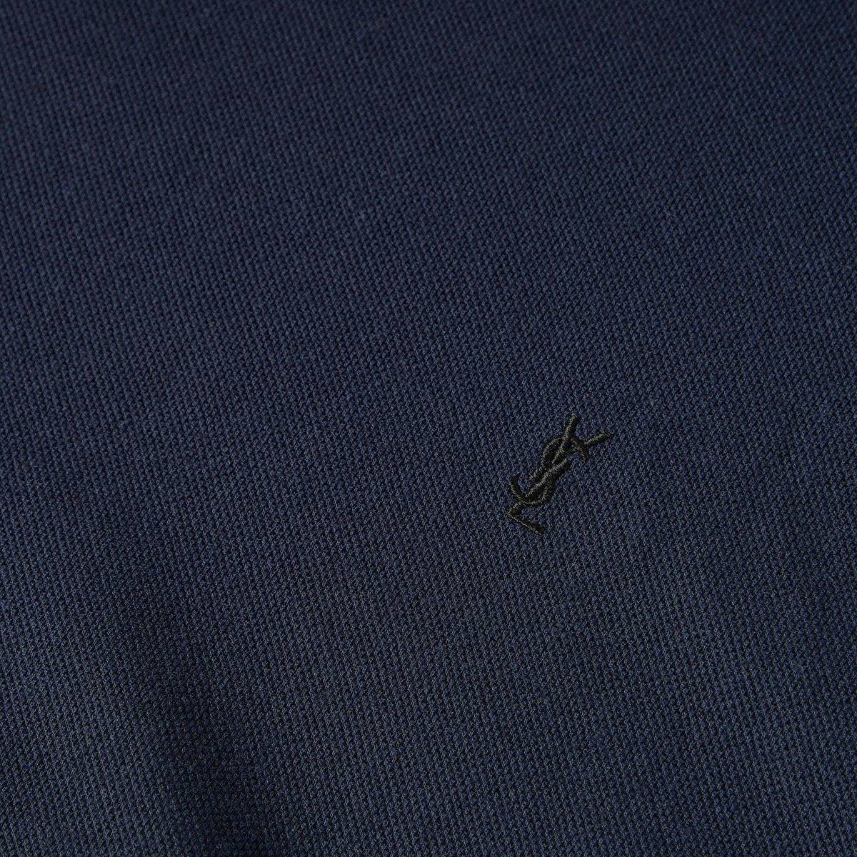 Close-up of navy knit T-shirt fabric with small embroidered logo