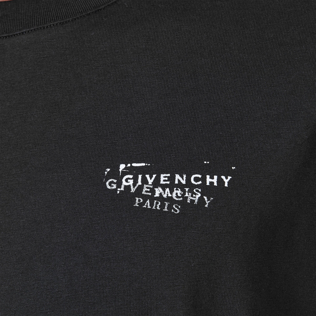 Close-up: black T‑shirt with white "GIVENCHY PARIS" logo stamp print