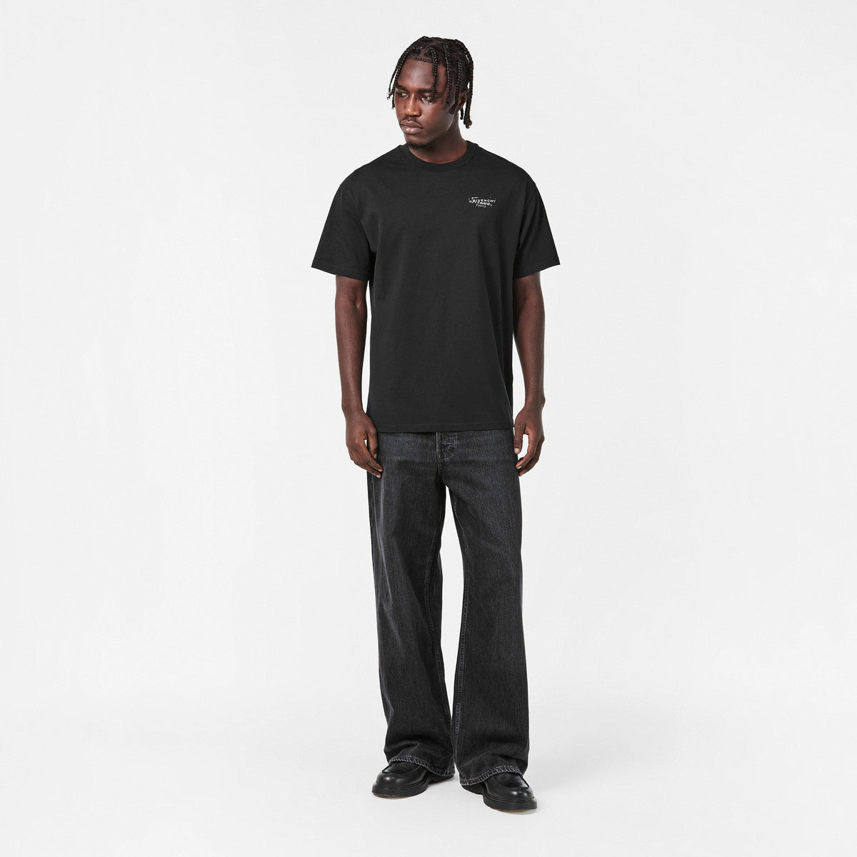 Black crew-neck T‑shirt with small chest logo print, worn with dark jeans