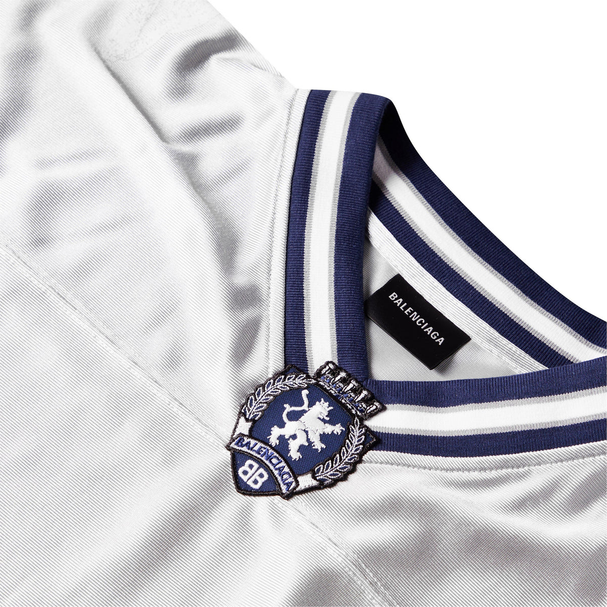 Close-up of Balenciaga T-shirt collar detail, blue striped rib and logo patch