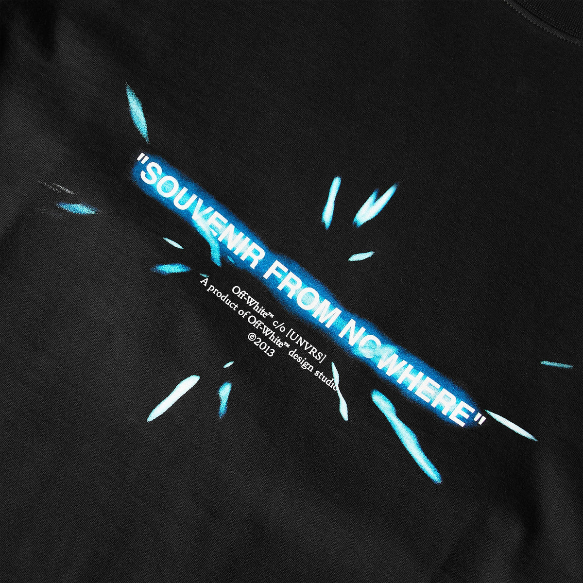 Close-up: black T-shirt front graphic text “SOUVENIR FROM NCWHERE” in blue