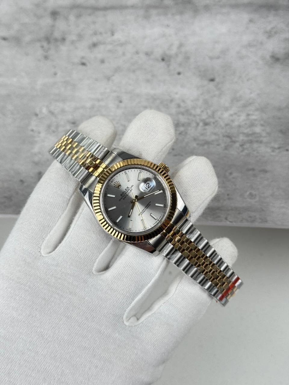 Two-tone Rolex wristwatch on white glove, silver dial and fluted bezel