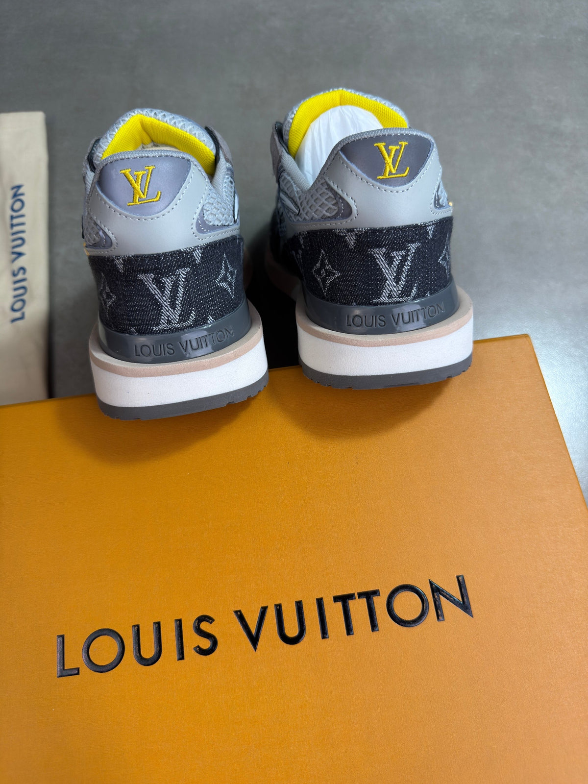 Grey Louis Vuitton trainers with yellow lining, back view showing heels