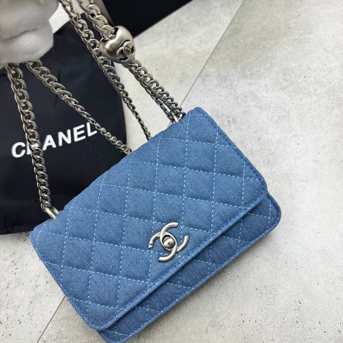 Blue quilted denim flap bag with silver chain strap and C-shaped logo clasp