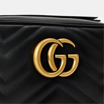 Close-up of gold-tone GG hardware on black chevron-quilted leather.