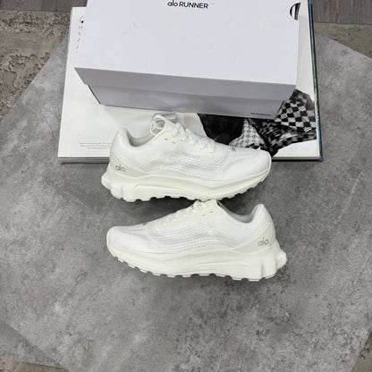 White lace-up training shoes with mesh-like texture and thick treaded sole