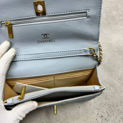 Light blue quilted leather shoulder bag with top flap, gold chain and hardware, interior visible