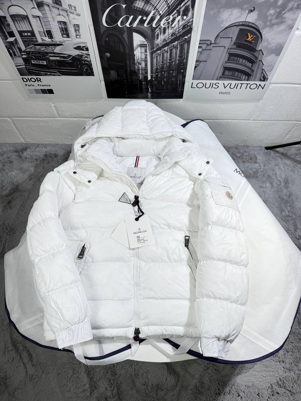 White Moncler puffer jacket featuring hood, zipper, and multicolor stripe on collar