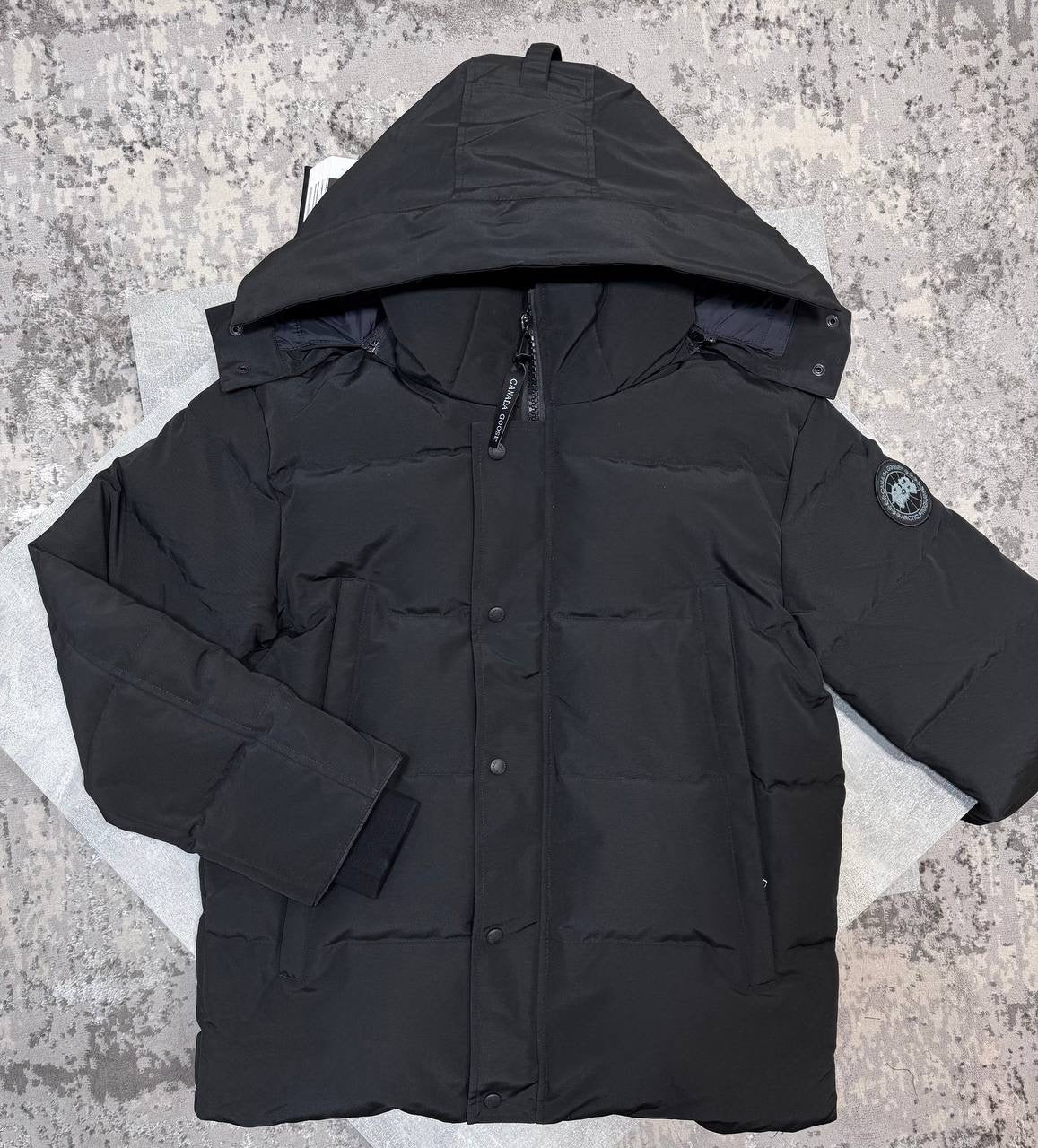 Black CG coat with structured hood, front zipper, and sleeve logo patch