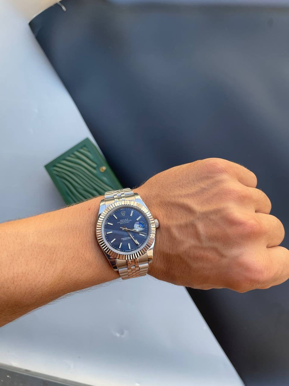 Rolex steel bracelet watch with blue dial, bezel markings, and luminous hands