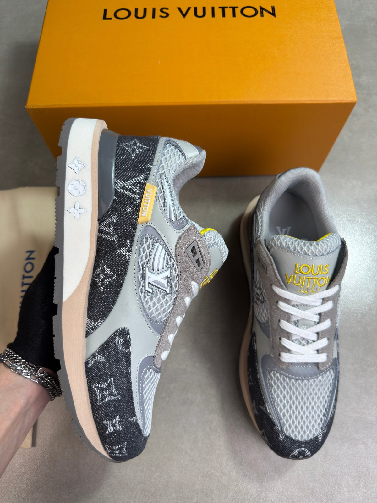Grey and black Louis Vuitton trainers, angled side view with white laces