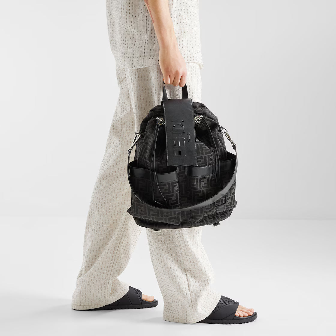Black rubber slides worn with thick outsole and embossed strap pattern