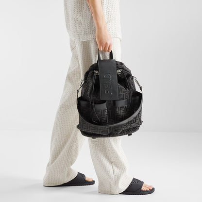 Black rubber slides worn with thick outsole and embossed strap pattern