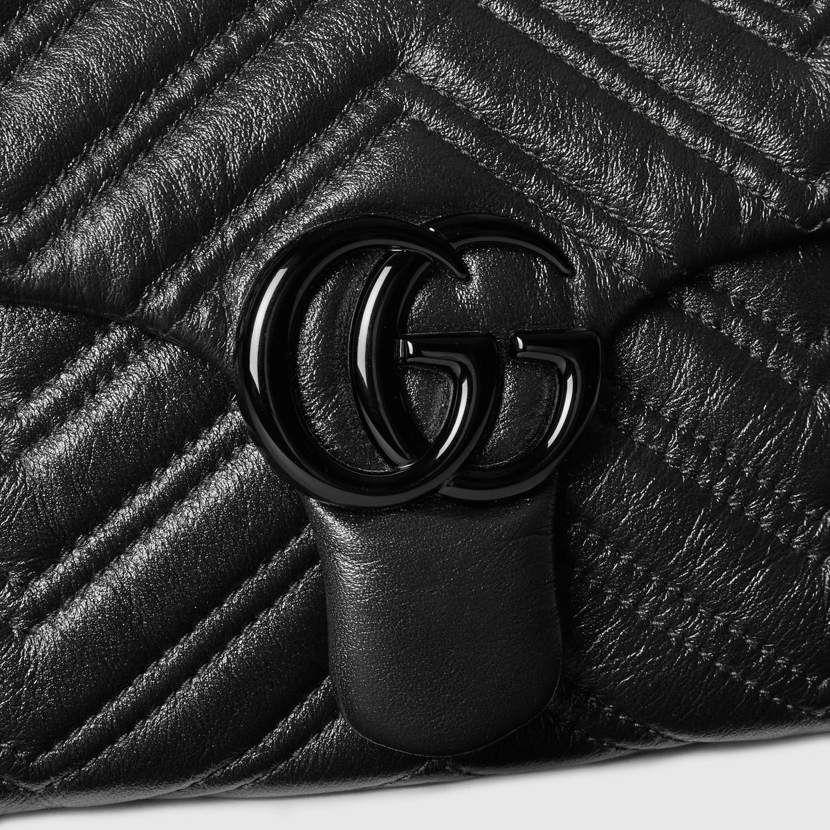 Close-up of black GG Marmont clasp on quilted leather chevron bag