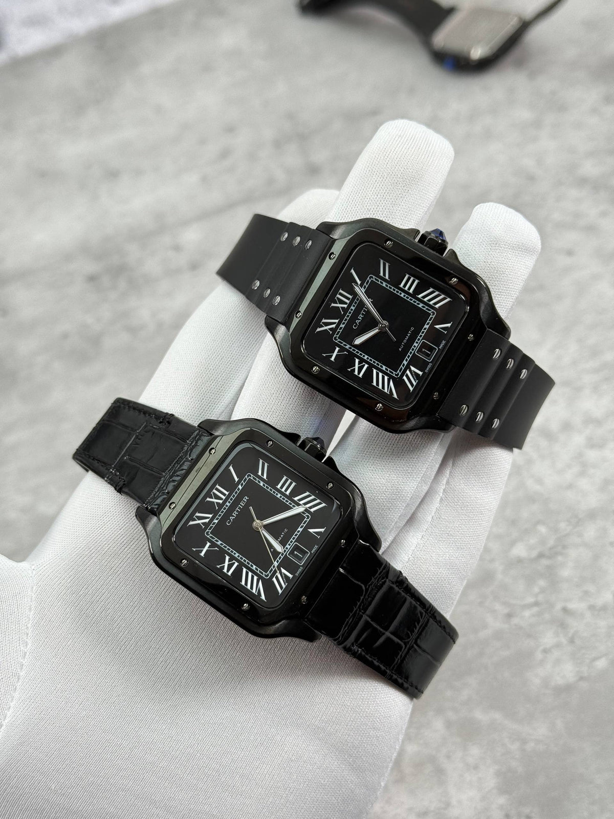 Cartier Santos watch pair with black dial and black straps, one leather one rubber