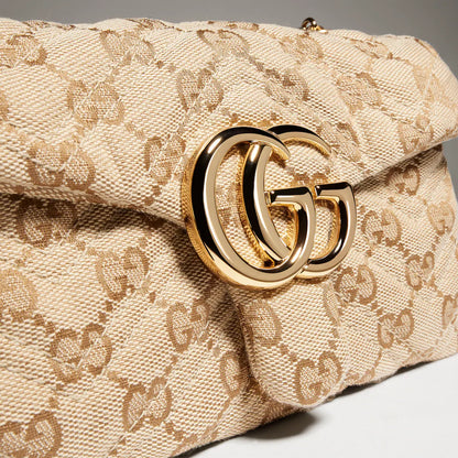 Close-up of GG Marmont mini bag clasp on beige monogram canvas with gold hardware
