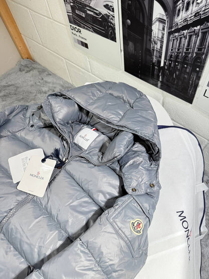 Light gray Moncler puffer jacket with hood, snap buttons, and logo crest patch
