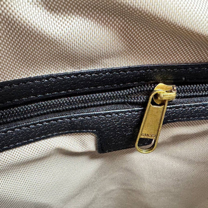 Black zipper pull with gold Gucci GG hardware on dark gray monogram lining