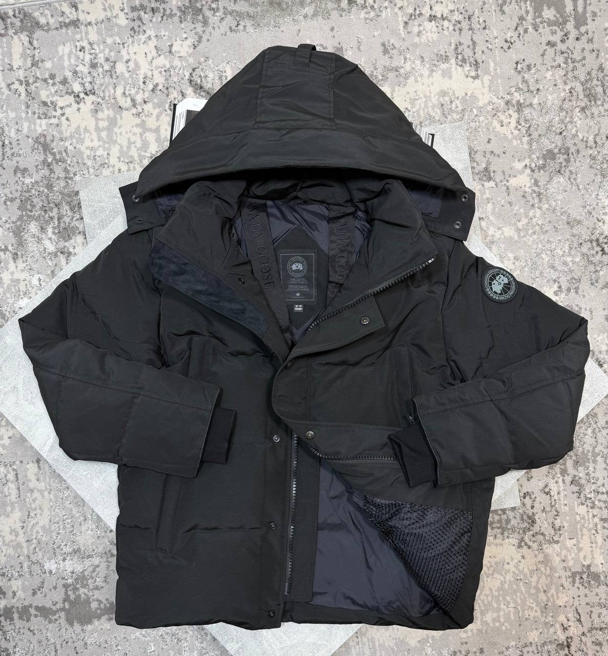 Black CG coat with hood, button front, zip detail, and round sleeve logo patch