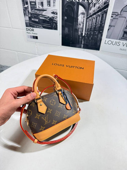 Monogram canvas handbag with tan leather edging and red crossbody strap, angled view
