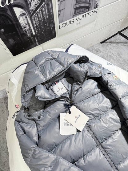 Light gray Moncler puffer jacket with hood, zipper front, and attached size tag