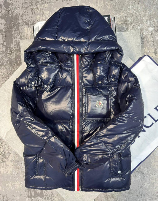 Navy puffer jacket with hood and red-trimmed front zipper, chest patch