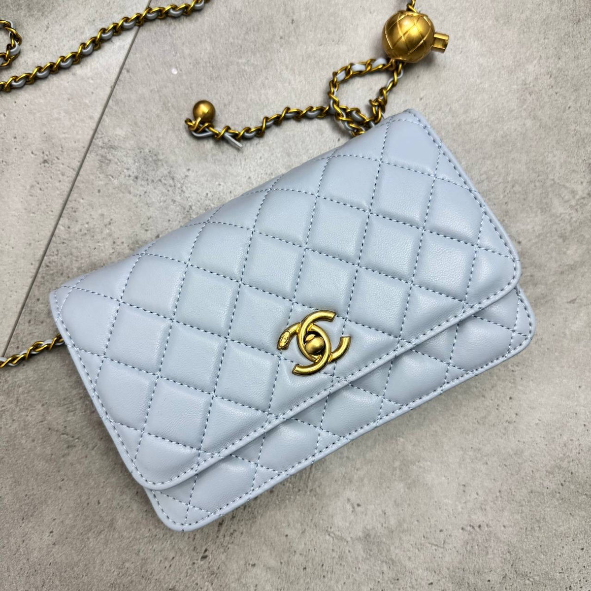 Light blue quilted flap shoulder bag with gold chain and CC clasp, bell charm